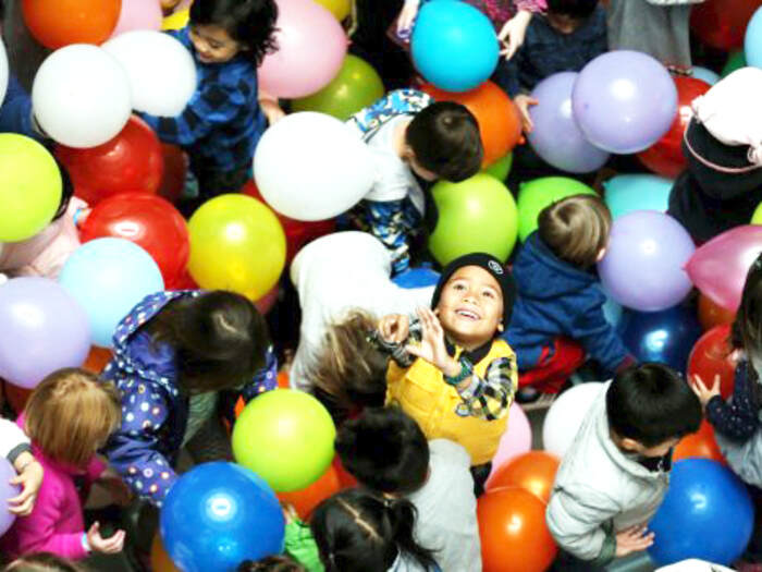 Children playing in balloon drop during daytime New Year's Eve celebration