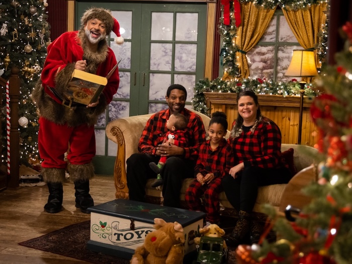 santa solas black santa in a christmas scene with two parents and two children. baby looks at santa