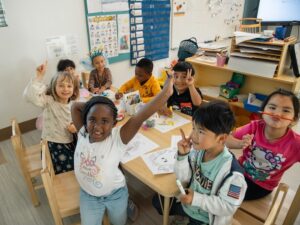 8 kindergarten students making art at a table