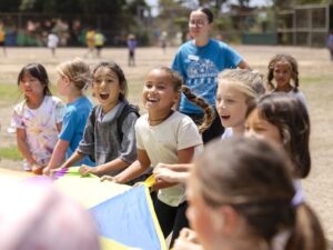 kids and a counselor playing with a giant parachute in a field