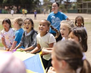 kids and a counselor playing with a giant parachute in a field