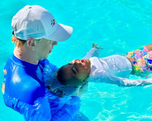 adult swimming with small child