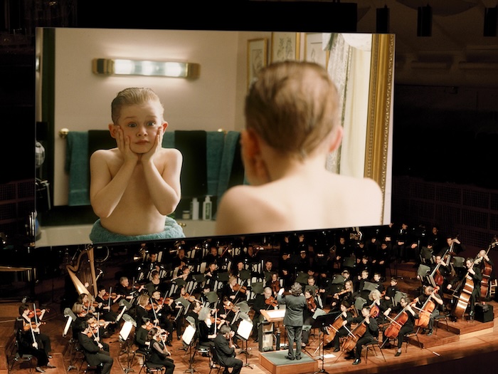Home alone movie on the big screen above a full symphony orchestra