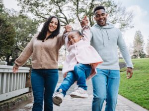 two parents swinging a child by her arms