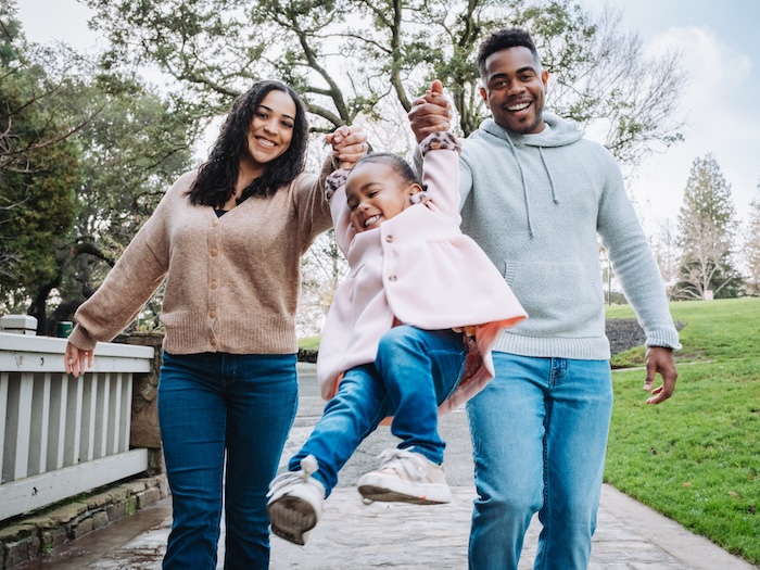 two parents swinging a child by her arms