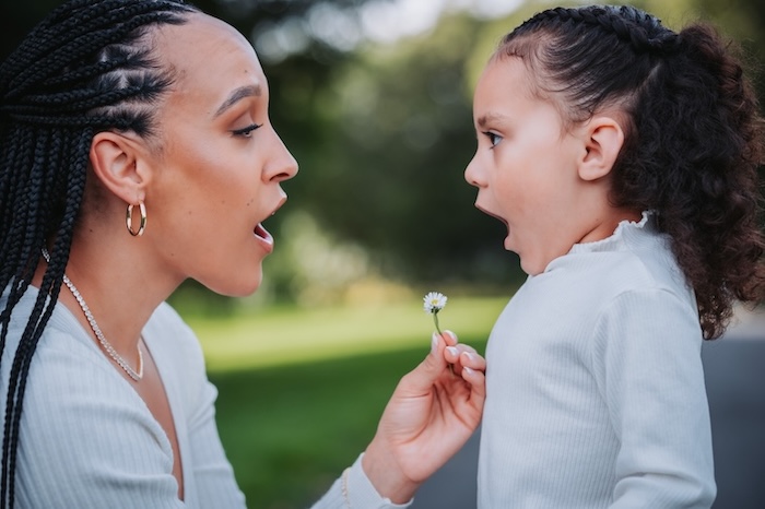 a mom and daughter making a wish on a dandelion. both are wearing white shirts