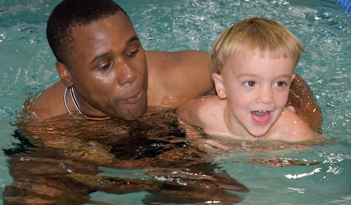 man helping young child to swim in pool