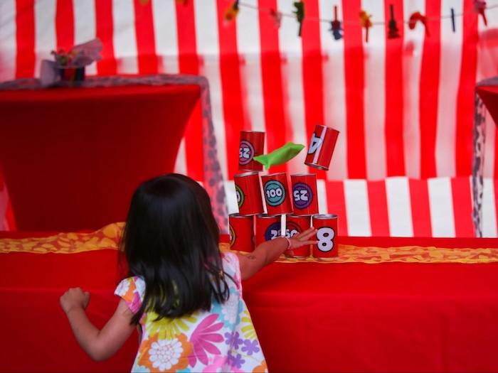 child knocking over cans in a carnival game red background