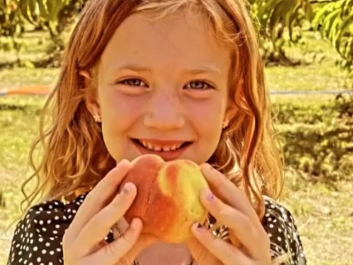 smiling girl holds peach