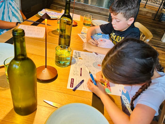 two kids drawing at a restaurant table