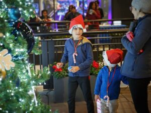 two boys wearing santa hats in front of a christmas tree