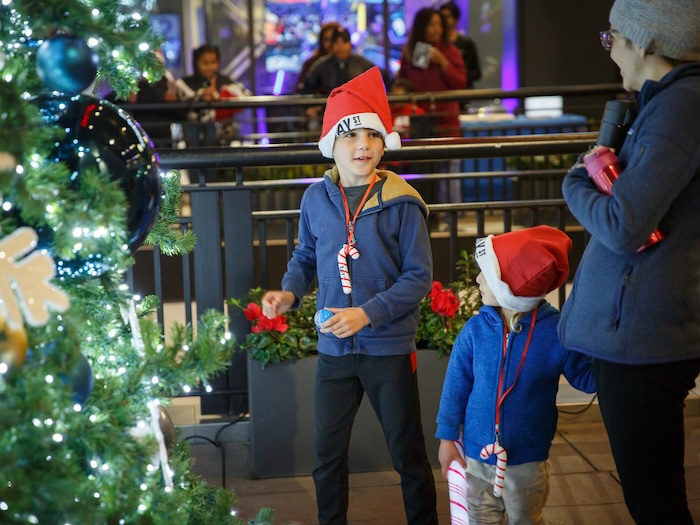 two boys wearing santa hats in front of a christmas tree