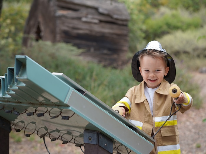 child dressed as fire fighter on a play structure