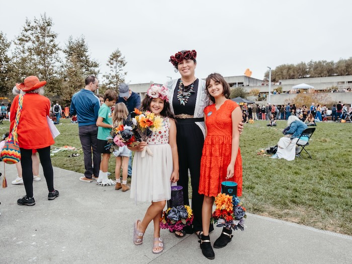 three people standing at a festival at omca