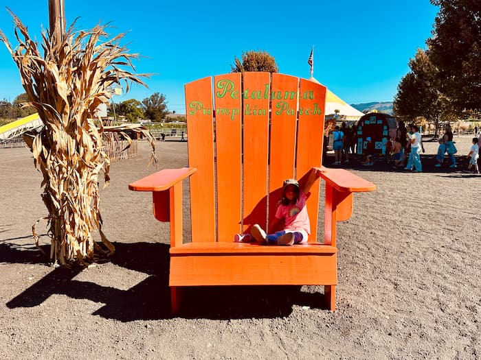 girl sitting in a giant orange chair outside