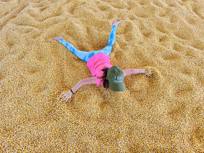 girl playing in corn sand box