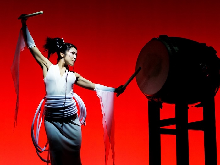 Drum Tao’s The Best woman drumming against red background