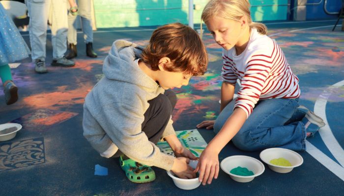 two children making chalk art on the play yard at a school