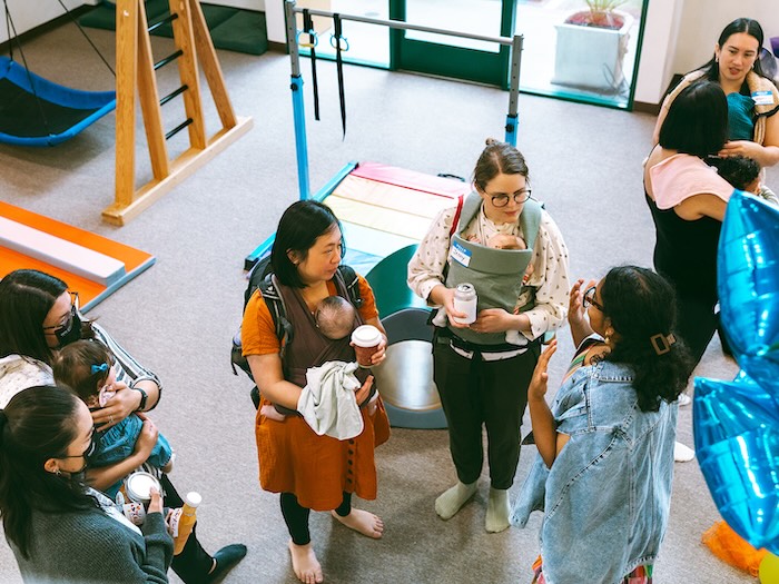 Kula founder lower right speaks with women and babies at spirited play labs