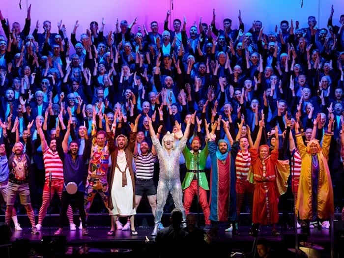 San Francisco Gay Men’s Chorus performing on risers with an array of holiday characters in the front row