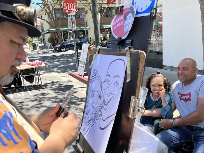 father and daughter having a sketch drawn by an artist