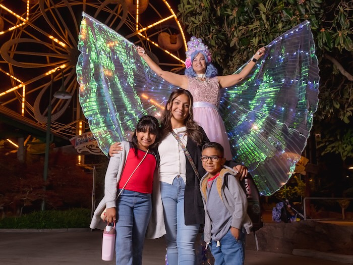 family in front of a costumed fairy at night
