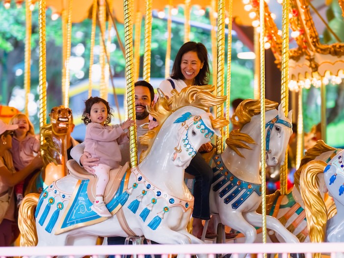 children and adults on a carousel merry go round riding on a white horse