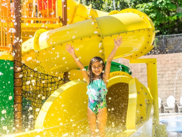 child standing in front of yellow water slide