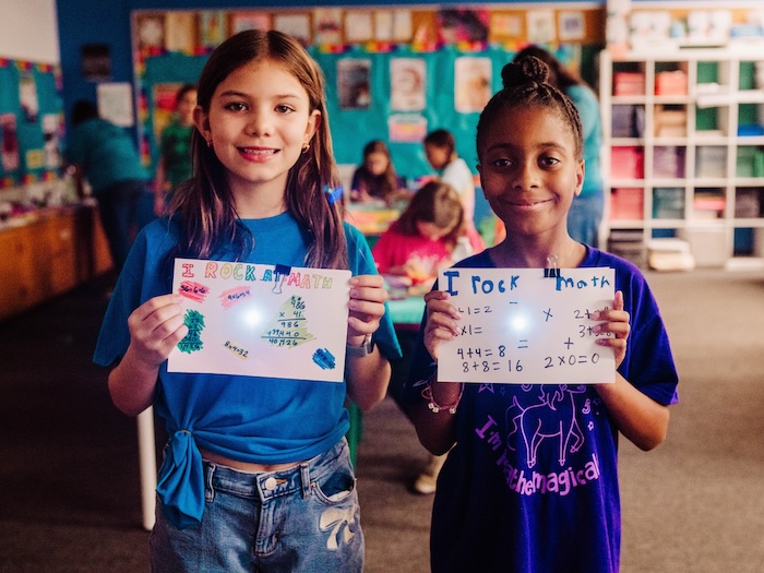 two girls holding math based artwork