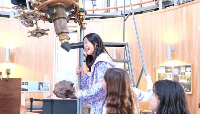 Girls looks through telescope