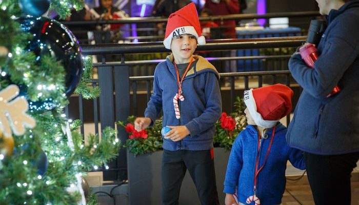 two boys wearing santa hats in front of a christmas tree