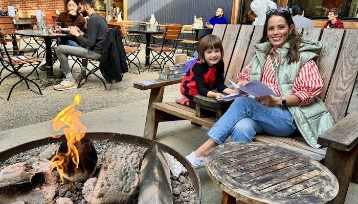 adult and child reading at the fire pit of drake's patio seating
