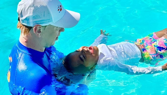 adult swimming with small child
