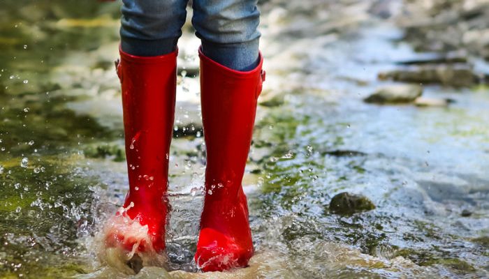 Child in red rainboots playing in the rain
