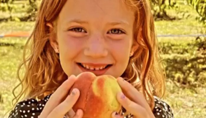 smiling girl holds peach